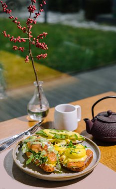 Eggs benedict on english muffin with smoked salmon, lettuce salad mix and hollandaise sauce