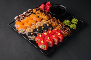 Traditional japanese food - sushi, rolls and sauce on a dark background