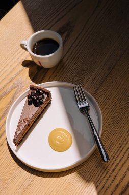 Chocolate cake with a coffee cup on wooden table