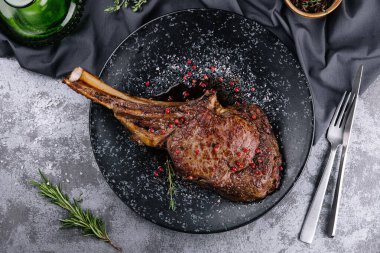 Grilled pork steak with bone in sauce on black plate