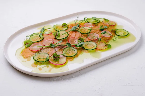 Buffet serving of pickled salmon slices with radish, cucumber