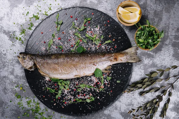 Grilled spicy fish on black plate, top view