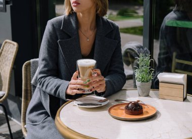 Kafede kek yiyen ve latte içen bir kadın.