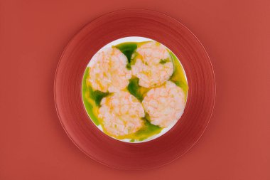 Kırmızı tabakta pesto soslu karides.