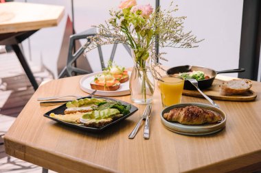 Kahvaltıda kruvasan, Benedict, omlet, somon bruschetta ve haşlanmış yumurta var.