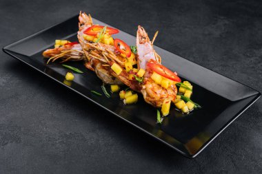 Siyah tabakta ızgara karides şişi.