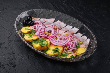 Fırında patatesle doğranmış ringa balığı ve cam tabakta marine edilmiş soğan.