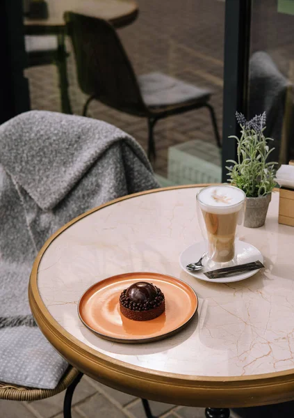 Latte coffee with cake on the table in the outdoor cafe