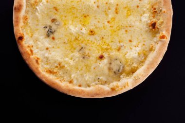 Siyah arka planda dört peynirli pizza.