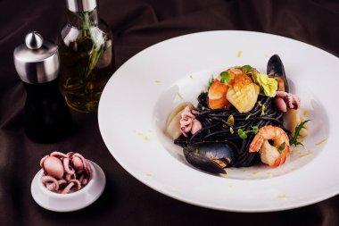 siyah beyaz tabakta su ürünleri spagetti