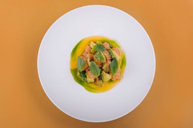 Avokadolu somon ve beyaz tabakta fesleğen.