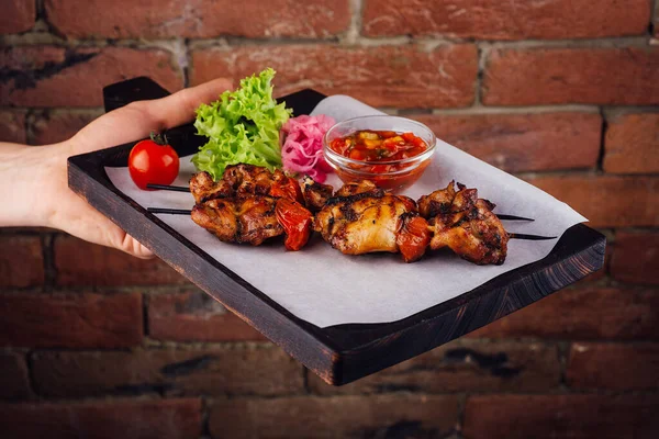 Chicken kebabs with tomatoes sauce on a board