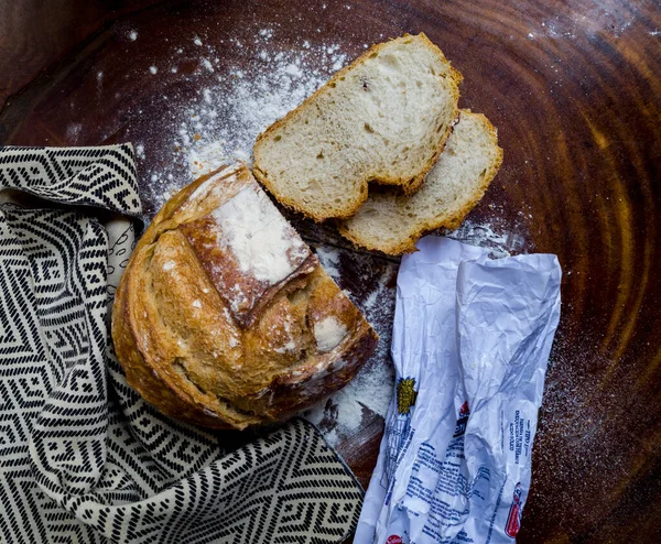 Italian bread sliced with cloth with African illustration and flour packet over wood and white flour.