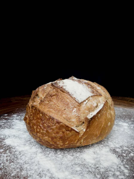 Italian bread on wood and white flour on a black background.