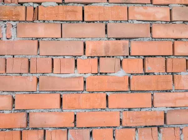 photo of a building wall with red brick masonry, which has suffered damage to its structure over time