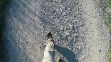 Toskana 'da bir patikada yürüyen bir adamın ayakları. Yolda yürüyen bir adam, çakıl ve gri kum