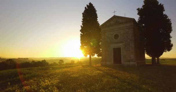 Luftfoto af forladt kirke i Toscana under solnedgang. Gyldent sollys skinner på landet. – Stock-video