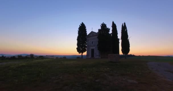 Aerial view of isolated church in Tuscany land during sunset. Colored sunset at the back of desolated church on top of hill — Stock Video