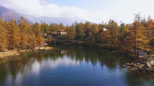 Vista aérea Voando sobre o lago da montanha no outono, folhagem de cor. Sobre a água cristalina do lago de montanha, lugar característico. Fundo de fadas paisagem montesa pinhal floresta com nuvens no fundo. — Vídeo de Stock