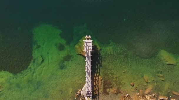 Vista aérea superior da pequena ponte de madeira no lago da montanha no outono. Sobre a água cristalina do lago de montanha, pedras para um lugar característico da montanha. Natureza, felicidade, não humano, paz de sentido — Vídeo de Stock