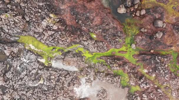 Vista aérea de la playa rocosa en las islas Feroe, rocas multicolores y prado verde, agua del océano en las rocas después de fuertes olas — Vídeo de stock