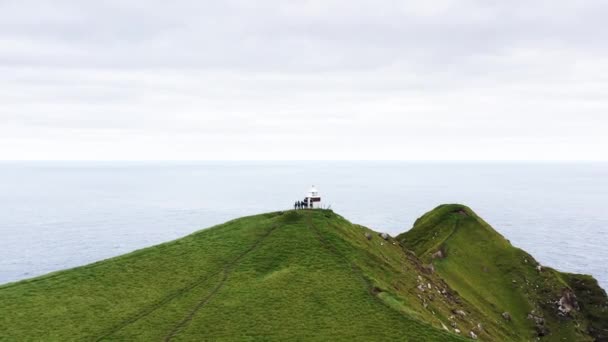 Flygfoto över fyren på toppen av grönt berg. Oceanen och öarna runt omkring. Scenisk antenn utsikt över fyren på bergstoppen, vild natur, inga människor och ingen mänsklig inblandning. — Stockvideo