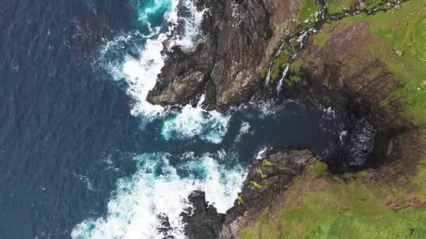 Luftaufnahme von Wellen brechen auf Felsen der Färöer-Inseln Klippen in einem blauen Ozean.Drohne Luftaufnahmen der grünen Natur und des Ozeans. — Stockvideo