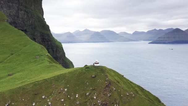 Flygfoto över fyren på toppen av grönt berg. Oceanen och öarna runt omkring. Scenisk antenn utsikt över fyren på bergstoppen, vild natur, inga människor och ingen mänsklig inblandning. — Stockvideo