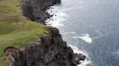 Hava manzaralı yüksek kaya kayalıkları, okyanus dalgaları kayalıklara çarpıyor. Vahşi doğa, vahşi yaşam, vahşi insanlar yok, gökyüzünde bulutlar, manzara yok.