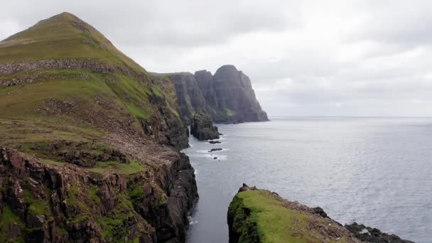 Widok z lotu ptaka na ogromne klify na wyspach Faroe, zielone skaliste góry, potężne fale oceaniczne, w pochmurny letni dzień, zielona łąka i skała w dzikiej przyrodzie, dziki nie ma domu. — Wideo stockowe