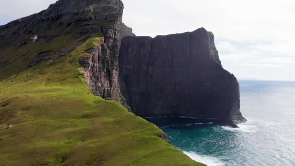 Onderdeel van een serie, luchtfoto 's van de beroemde klif op de Faeröer. Vlucht over groen gras en onverharde weg van de klif in een bewolkte dag. — Stockvideo