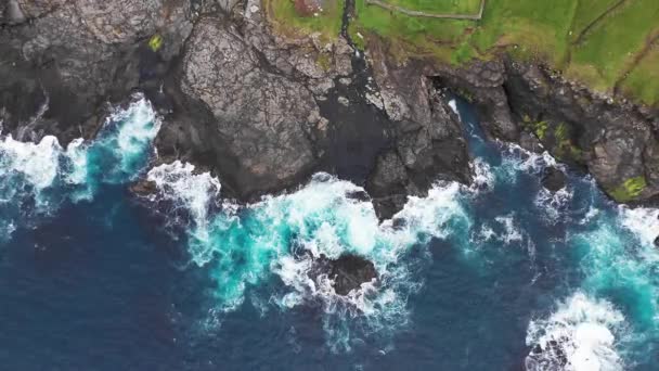 Luchtfoto van golven breken op rotsen van Faeröer eilanden kliffen in een blauwe oceaan.Drone Luchtfoto Beelden van groene natuur en de oceaan. — Stockvideo