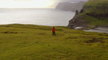 Yürüdükten sonra dinlenen insanın havadan görünüşü, sahil manzarası. Genç adam gün batımında vahşi manzaraya, uçuruma, denize, kıyılara hayran..