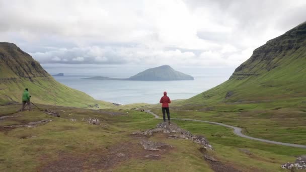 Aerial view of unrecognizable woman looking at the panorama, islands, ocean, green mountain and rock cliffs.Impressions of the fascinating archipelago of the Faroe Islands in the North Atlantic Ocean — Stock Video