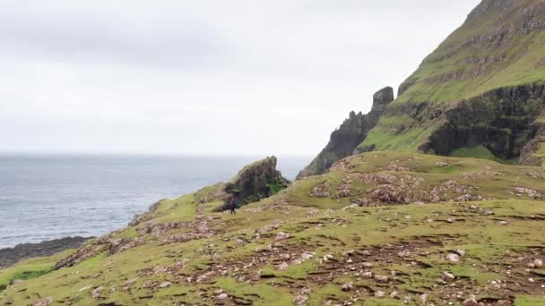 Vista aérea trasera de enormes acantilados en las islas Feroe, montaña rocosa verde, potentes olas oceánicas, en un día nublado de verano, prado verde y roca en la naturaleza salvaje, salvaje sin casa. — Vídeo de stock