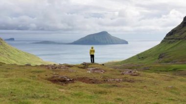 Panorama, adalar, okyanus, yeşil dağ ve kaya kayalıklarına bakan tanınmayan bir adamın havadan görünüşü. Kuzey Atlantik Okyanusu 'ndaki Faroe Adaları' nın büyüleyici takımadalarının izleri.