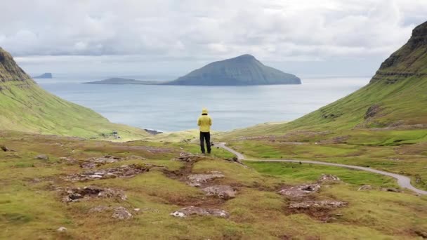 Vista aérea del hombre irreconocible que mira el panorama, las islas, el océano, la montaña verde y los acantilados de rocas.Impresiones del fascinante archipiélago de las Islas Feroe en el Océano Atlántico Norte — Vídeos de Stock