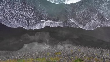 Okyanus dalgaları ve suyun kumlu sahile yukarıdan çarptığı güzel bir sahil manzarası. Sahile vuran dalgalarla Faroe Adaları plajı. İnsan yok, destansı dramatik kumsal.