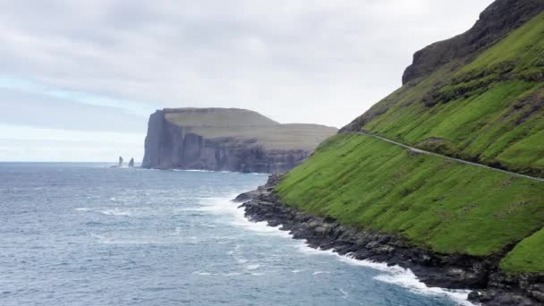 Прекрасний вигляд Різіна і Келлінгінга, гіганта і відьма на острові Фарер. океанські хвилі на скелястому пляжі, морська піна на фоні, зелена гора, дика природа, дикі люди — стокове відео