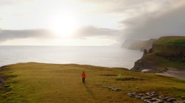 Yürüdükten sonra dinlenen insanın havadan görünüşü, sahil manzarası. Genç adam gün batımında vahşi manzaraya, uçuruma, denize, kıyılara hayran..