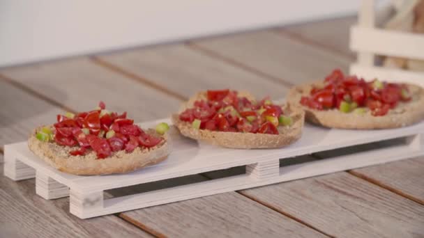 Zbliżenie części włoskiego aperitifu: pomidor, bazylika na chlebie. Żywność palcowa — Wideo stockowe