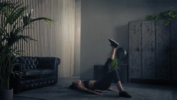Mulher morena atlética fazendo ponte de glauta de perna única interior em sportswear. Movimento lento, vista lateral — Vídeo de Stock