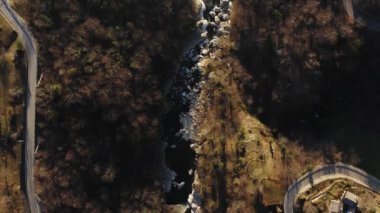 Hava manzaralı dağ manzarası, nehir dağdan geçiyor, kıvrımlı yol nehri geçiyor. Her iki tarafta çam ormanı.