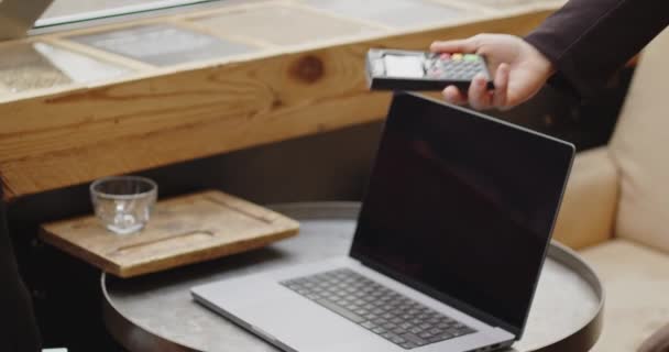 Κοντινό πλάνο μιας γυναίκας που κάθεται σε ένα καφέ με φορητό υπολογιστή, πληρώνοντας με πιστωτική κάρτα.mart πληρωμή, ανέπαφη πληρωμή, e-money, ψηφιακό χρήμα. Γυναίκα που δουλεύει, σπουδάζει σε καφετέρια. — Αρχείο Βίντεο