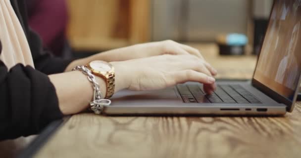 Close-up of caucasian woman working in a coffee shop. Woman in smart casual suit writing about new project on digital laptop. Remote working jobs. Footage made through the window — Stock Video