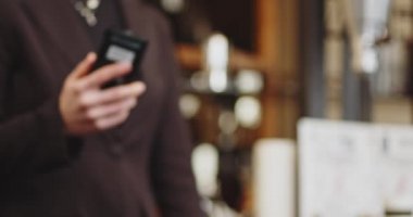 NFC teknolojisini kullanarak ödeme yapan yakın plan kadın öğrenci kıza, iş kadınına telefonsuz ödeme yapıyor. Elektronik ödeme makinesi ya da kart okuyucusuyla ödemeyi telefonla yapıyor. Nakitsiz cüzdanda e-para