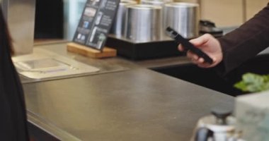 PIN kodunu girmeden kredi kartı ödeyen kadının yakın plan fotoğrafı, akıllı ödeme, ulaşılamaz ödeme, e-para, dijital para. Tıbbi maskeli barmen kadın, Cavid 'den sonra iş tekrar açıldı.