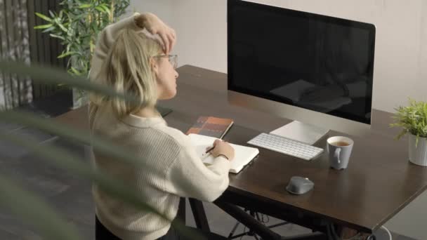 Kvinna tittar på monitorer dator, lyssna konferens, lektion, skriva och anteckna. Kvinna flyttar håret på en sida — Stockvideo