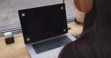 Kafkasyalı bir kadının kafeteryada dizüstü bilgisayarla yazışması. İnternetteki konferans sırasında dizüstü bilgisayarda yazan, kulaklıkla dinleyen akıllı takım elbiseli bir kadın. Uzak çalışma işleri.