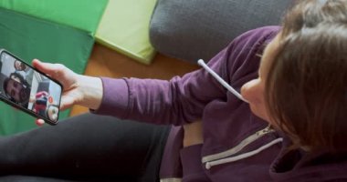 Annem evde akıllı telefondan ailesiyle konuşuyor. Kadınlar yerde oturup video çekiyor. İnternet, Teknoloji Konsepti, 4K Çözünürlük